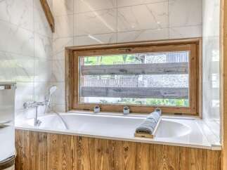 Experience luxury in this stunning bathroom featuring a modern bathtub and a serene view through the window.