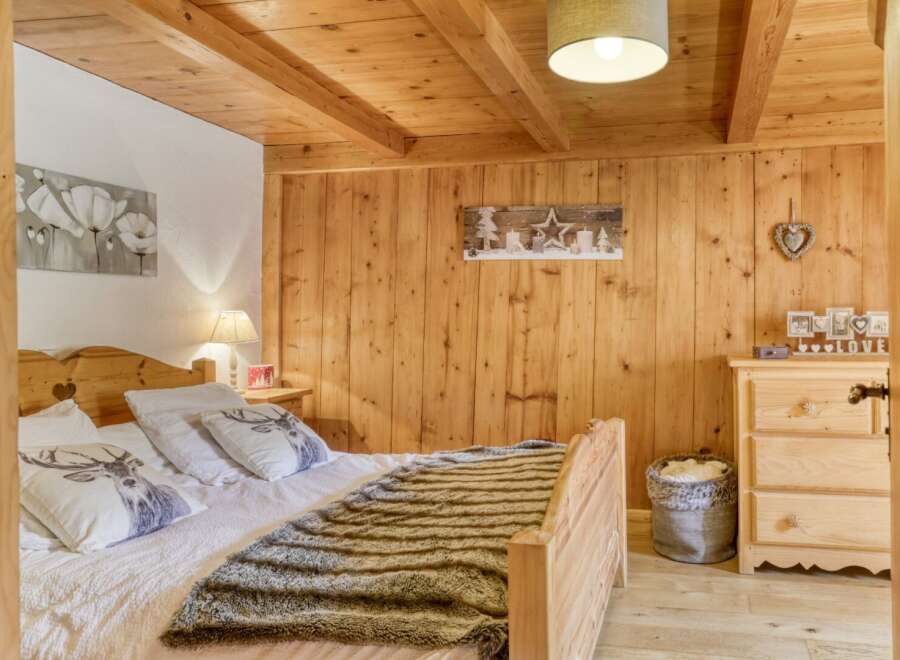 This cozy bedroom features a rustic wooden ceiling and walls, creating a warm and inviting atmosphere.