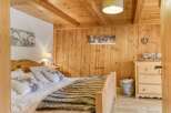 This cozy bedroom features a rustic wooden ceiling and walls, creating a warm and inviting atmosphere.