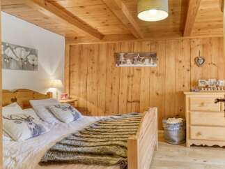 This cozy bedroom features a rustic wooden ceiling and walls, creating a warm and inviting atmosphere.