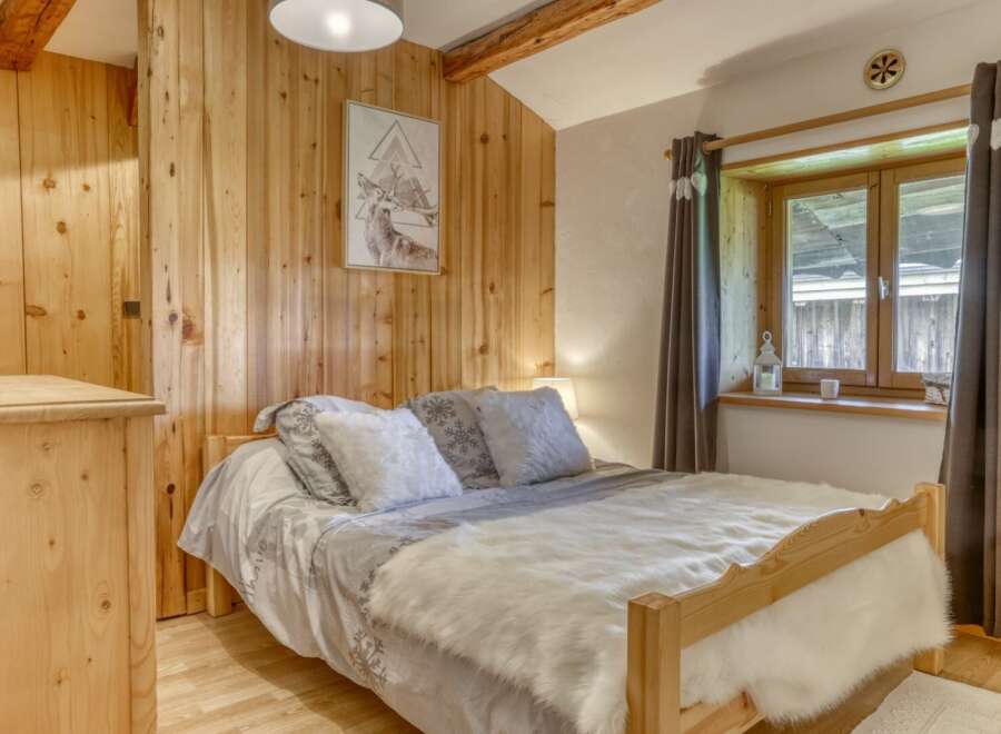 Discover the charm of this cozy bedroom, featuring a warm wooden interior and a comfortable bed.