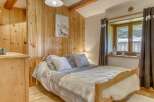 Discover the charm of this cozy bedroom, featuring a warm wooden interior and a comfortable bed.