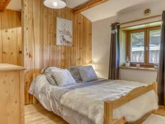 Discover the charm of this cozy bedroom, featuring a warm wooden interior and a comfortable bed.