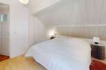 This charming bedroom features a cozy, sloped ceiling and a comfortable bed, perfect for a relaxing retreat.