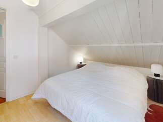 This charming bedroom features a cozy, sloped ceiling and a comfortable bed, perfect for a relaxing retreat.