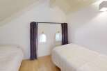 This charming bedroom features unique architectural details, including arched windows and a sloped ceiling.