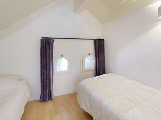 This charming bedroom features unique architectural details, including arched windows and a sloped ceiling.