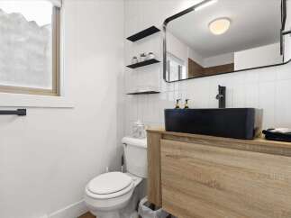 This modern bathroom features a sleek black sink and faucet, complemented by a stylish wooden vanity.