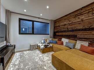 This stunning living space boasts a cozy sectional sofa and a unique wood-paneled accent wall, creating a warm and inviting atmosphere.
