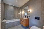 This modern bathroom boasts a sleek design with its gray tiled walls and flooring, creating a sophisticated and contemporary ambiance.