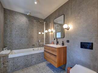 This modern bathroom boasts a sleek design with its gray tiled walls and flooring, creating a sophisticated and contemporary ambiance.