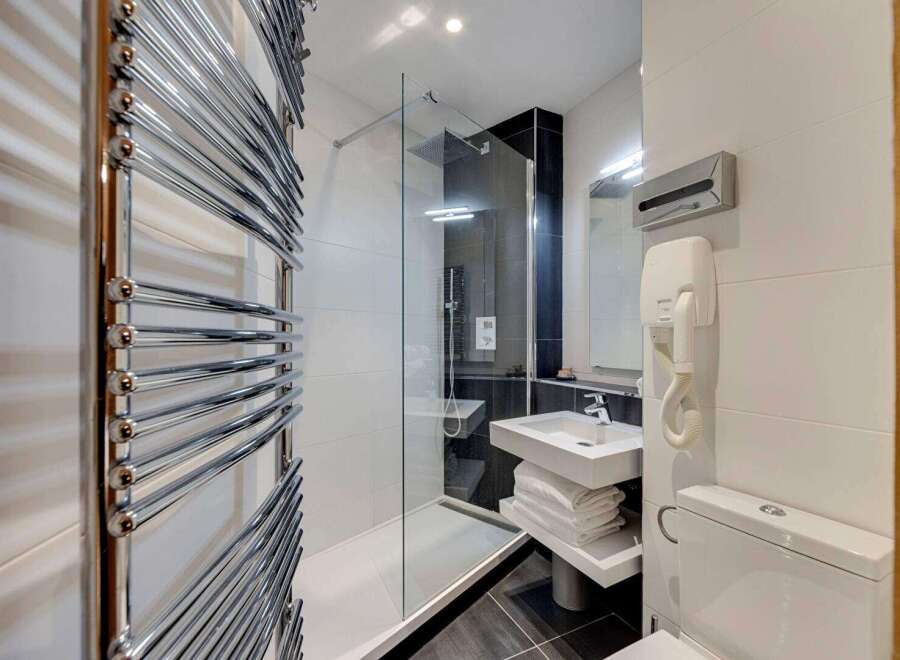 This modern bathroom features a sleek glass shower enclosure, perfect for a refreshing start to your day.