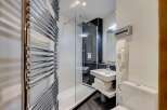 This modern bathroom features a sleek glass shower enclosure, perfect for a refreshing start to your day.