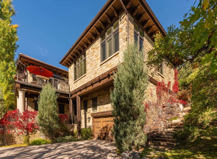 This stunning stone-clad home boasts a beautiful exterior with a wooden garage door and a charming balcony.