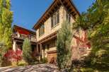 This stunning stone-clad home boasts a beautiful exterior with a wooden garage door and a charming balcony.