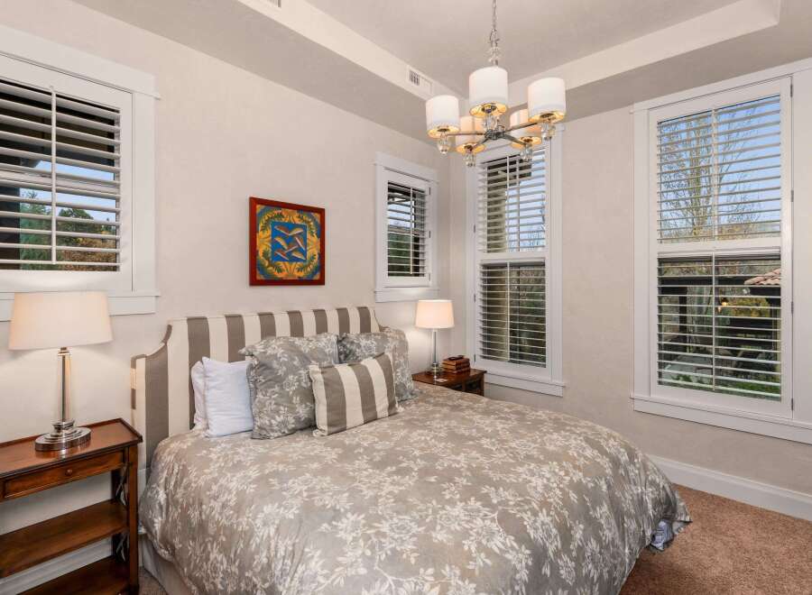 This elegant bedroom showcases a blend of comfort and style, featuring a cozy bed adorned with patterned bedding and plush pillows.