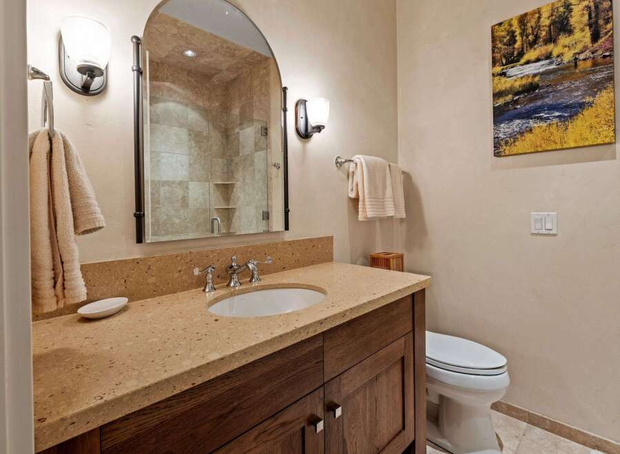 This luxurious bathroom features a stunning vanity with a natural stone countertop and a stylish sink.