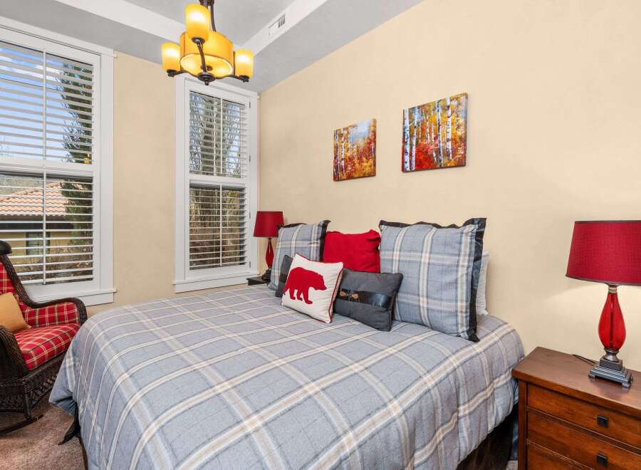 This cozy bedroom features a comfortable bed with a plaid comforter and decorative pillows, creating a warm and inviting atmosphere.