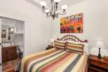 This charming bedroom features a cozy bed adorned with colorful striped bedding and pillows, creating a warm and inviting atmosphere.