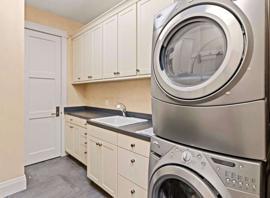 This laundry room offers a blend of functionality and style, featuring a modern stacked washer and dryer set.