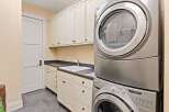 This laundry room offers a blend of functionality and style, featuring a modern stacked washer and dryer set.