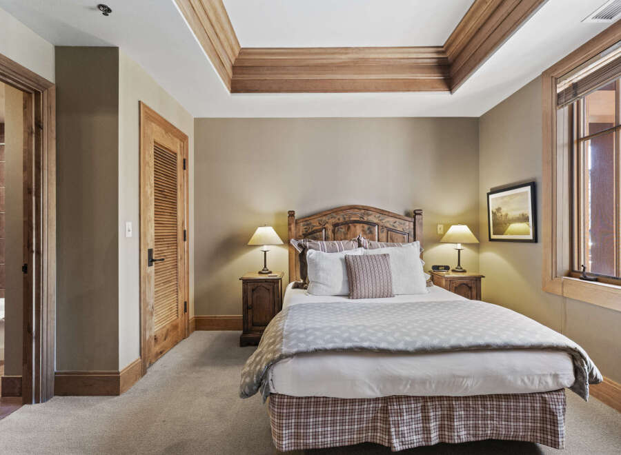 This cozy bedroom features a beautifully crafted wooden headboard and matching nightstands, creating a warm and inviting atmosphere.