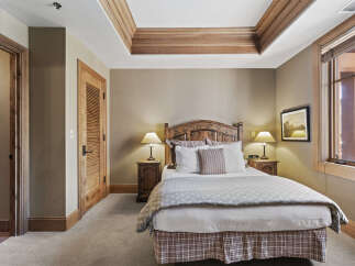 This cozy bedroom features a beautifully crafted wooden headboard and matching nightstands, creating a warm and inviting atmosphere.
