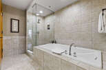 Indulge in the luxury of this spa-like bathroom, featuring a sleek glass-enclosed shower and a deep soaking tub.