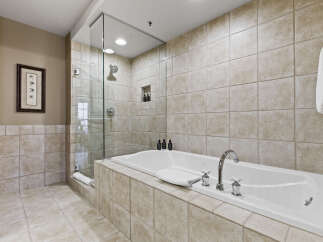 Indulge in the luxury of this spa-like bathroom, featuring a sleek glass-enclosed shower and a deep soaking tub.