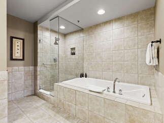 Indulge in luxury within this stunning bathroom, featuring a spacious soaking tub and a separate glass-enclosed shower.