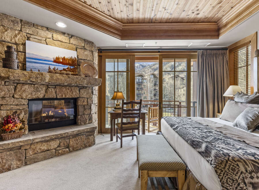 Experience luxury in this stunning bedroom featuring a cozy stone fireplace, perfect for chilly evenings.