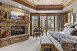 Experience luxury in this stunning bedroom featuring a cozy stone fireplace, perfect for chilly evenings.