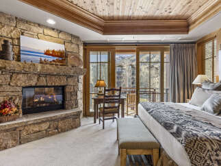Experience luxury in this stunning bedroom featuring a cozy stone fireplace, perfect for chilly evenings.