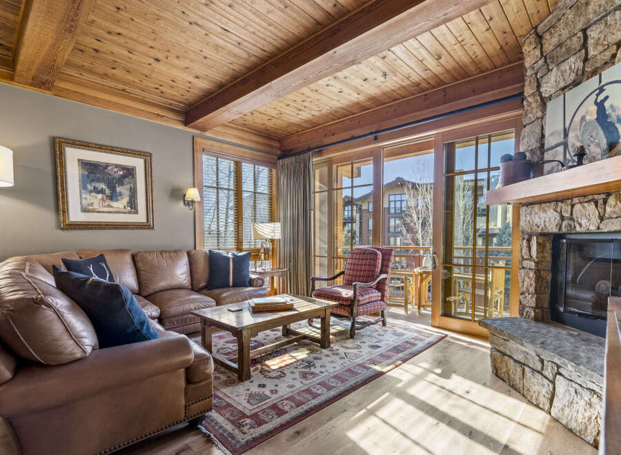 Step into luxury with this stunning living room featuring a cozy fireplace and a beautiful wooden ceiling.