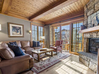 Step into luxury with this stunning living room featuring a cozy fireplace and a beautiful wooden ceiling.