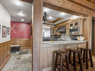 Step into rustic elegance with this stunning property, showcasing a beautifully designed kitchen with custom wood cabinetry and a sleek stainless steel refrigerator.