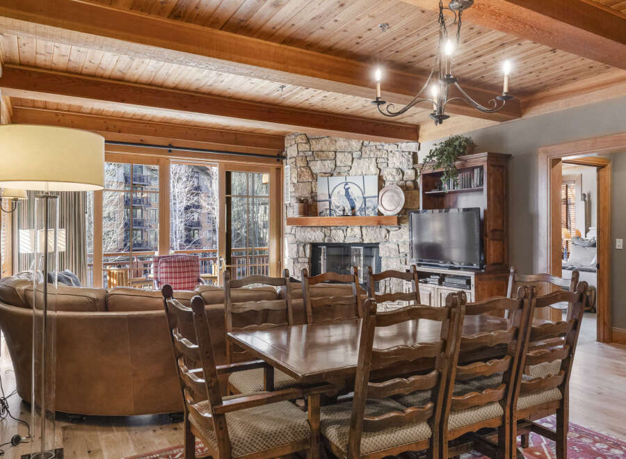 Experience luxury living in this stunning property, featuring a cozy living room with a stone fireplace and a beautiful wooden ceiling.