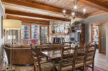 Experience luxury living in this stunning property, featuring a cozy living room with a stone fireplace and a beautiful wooden ceiling.