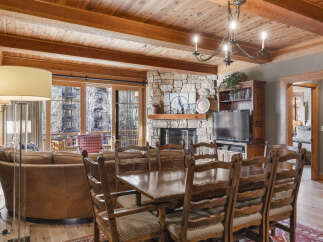 Experience luxury living in this stunning property, featuring a cozy living room with a stone fireplace and a beautiful wooden ceiling.
