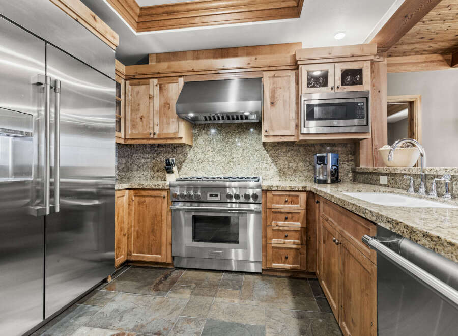 This stunning kitchen boasts top-of-the-line stainless steel appliances, including a refrigerator, range, and microwave.