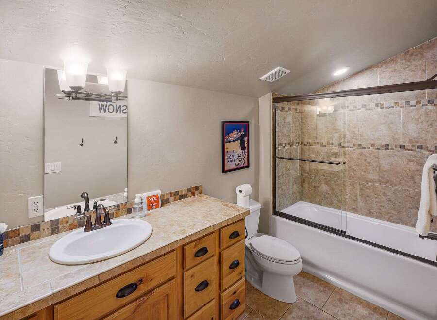 This inviting bathroom features a well-lit vanity area with a large mirror and ample storage.