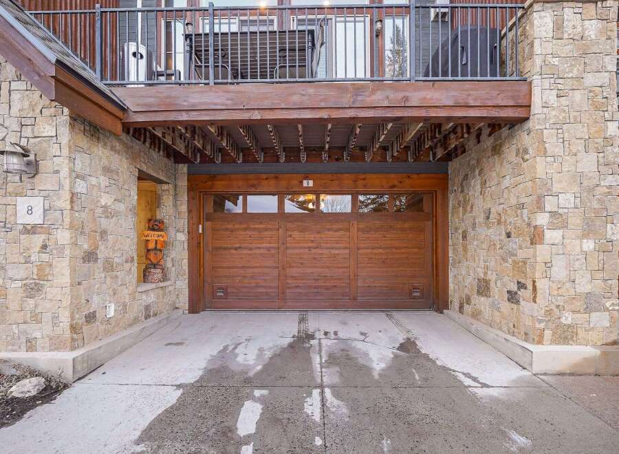 This stunning property boasts a beautiful stone exterior and a charming wooden garage door.