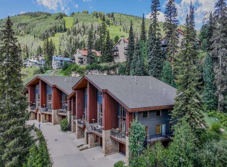 Experience luxury mountain living in this stunning property, nestled amidst a lush forest with breathtaking views of a ski slope.