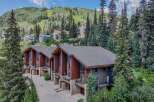 Experience luxury mountain living in this stunning property, nestled amidst a lush forest with breathtaking views of a ski slope.