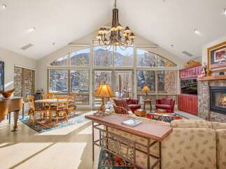 Experience luxury living in this stunning property featuring a grand living room with a soaring ceiling and breathtaking mountain views.