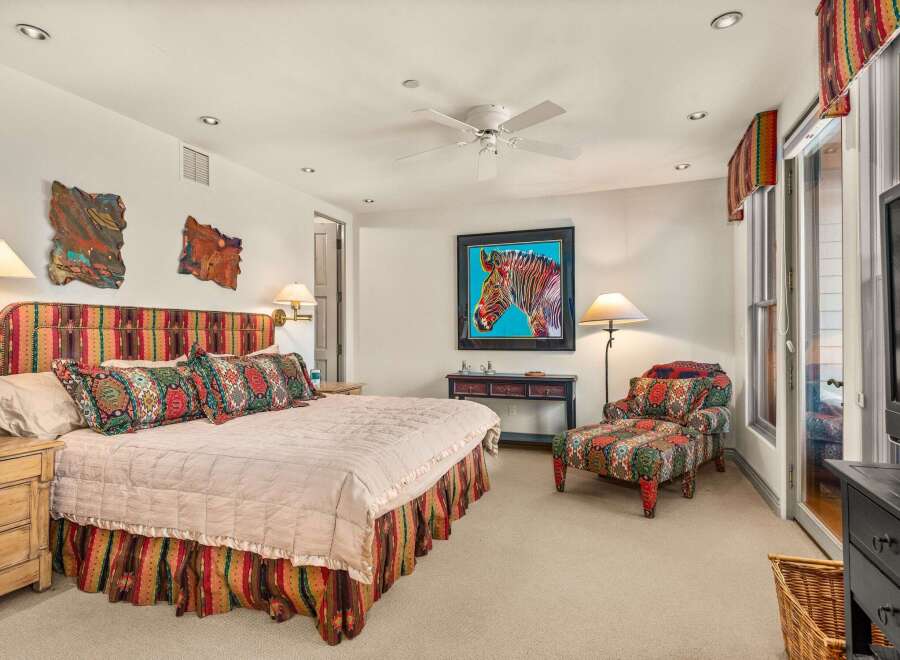 Step into a vibrant bedroom oasis! This space features a stunning zebra artwork, a cozy patterned armchair, and a beautifully designed bed with a matching headboard and bed skirt.