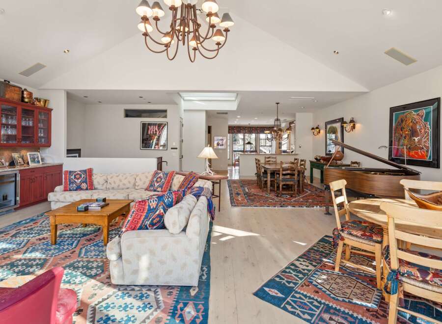 Step into luxury with this stunning property, featuring a spacious living area with a grand piano and a cozy dining space.