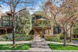 Charming townhouse featuring a multi-level stone and wood facade, complemented by lush landscaping and vibrant spring tulips.