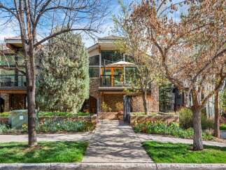 Charming townhouse featuring a multi-level stone and wood facade, complemented by lush landscaping and vibrant spring tulips.