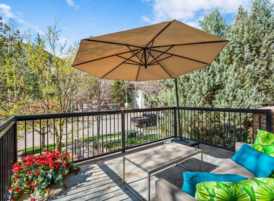 Enjoy the outdoors on this charming balcony, complete with a large umbrella for shade and comfortable seating.